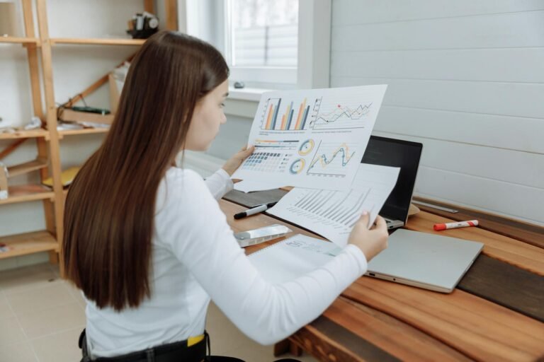 Woman reviewing business charts in a home office setting, showcasing remote work lifestyle.